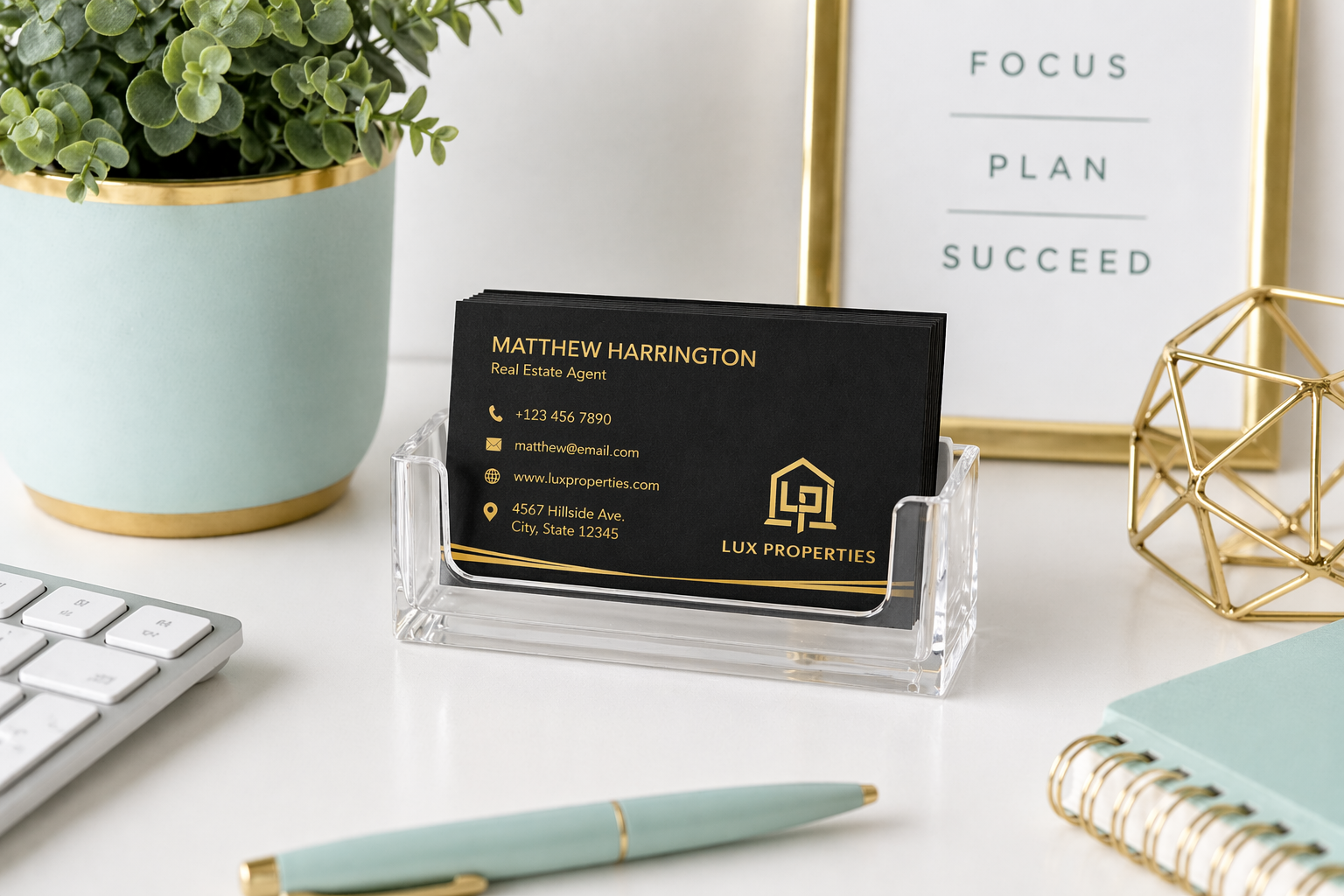 Business card holder with a business card on a desk with a plant and decor items.